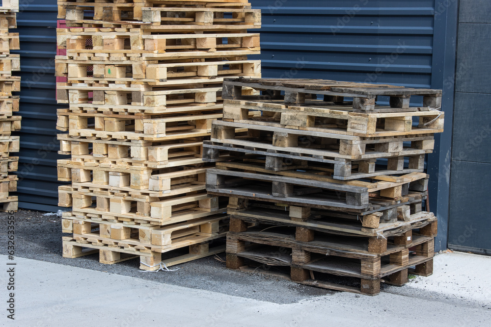 Stacks of old substandard wooden pallets stacked against a warehouse wall