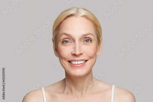 Portrait of happy blonde mature woman with shiny skin with mimic wrinkles