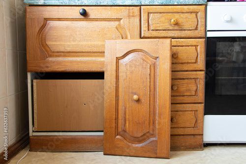 Old wooden kitchen cabinet in the kitchen with a broken door in a Ukrainian apartment, furniture repair
