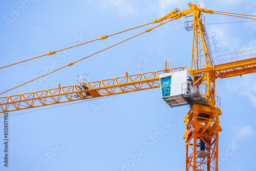 A blue slan surrounds the building under construction. Crane. Crane for lifting things in construction against sunset sky atmosphere. communities and large industrial construction zones.	 photo