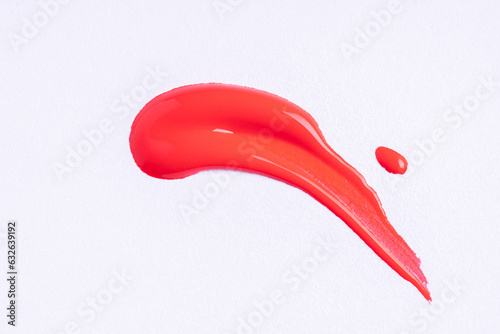 Round swatches of red paint on white paper background. Deep red swatch of lip gloss, cosmetic product stroke or paint.