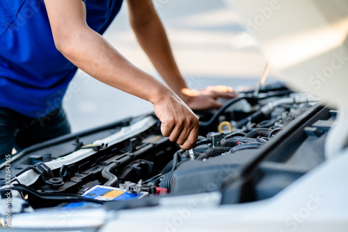 Auto mechanic repairman using a wrench working engine repair in the garage, changing spare parts, checking the mileage of the car, checking and maintaining service concept.