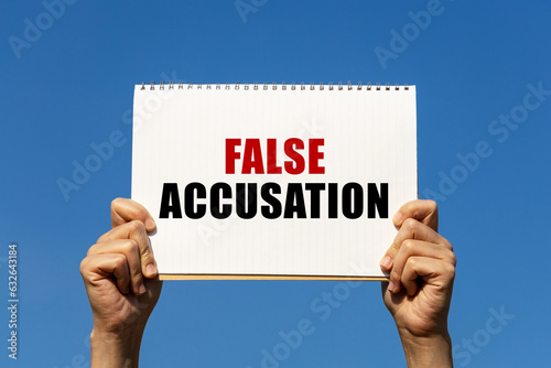 Canvas Print False accusation text on notebook paper held by 2 hands with isolated blue sky background