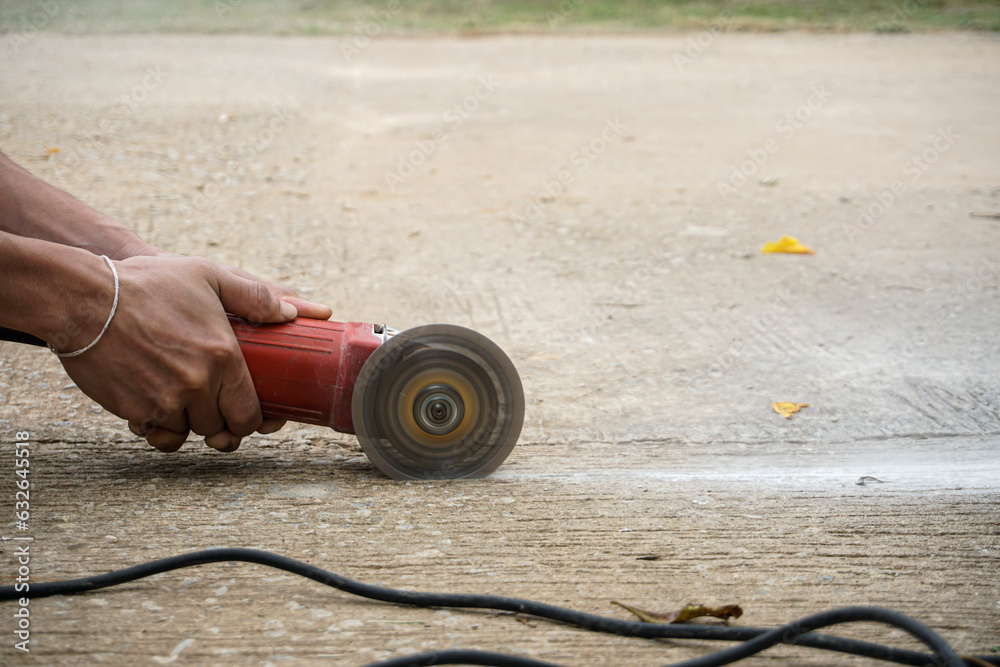 Obraz premium Worker using tool to cut concrete floor with dust