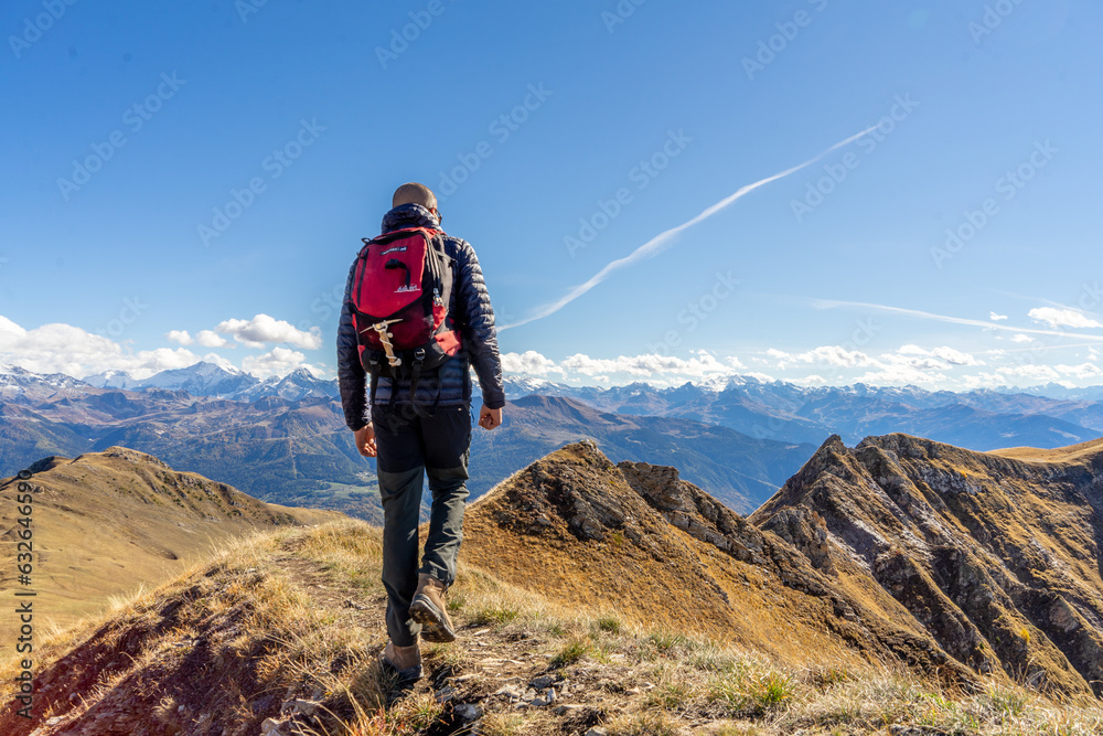 Fototapeta premium Jeune homme en train de randonner au sommet d'une montagne, en Savoie, dans les Alpes