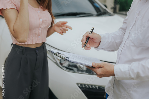 An insurance agent inspects the damaged vehicle and submits a post-accident claim form. Traffic accident and insurance concept