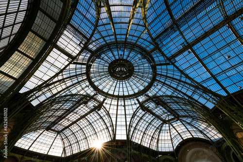 Historic glass roof with steel beam and rivet construction from the 19th century. Blue sky and low sun above the cupola of an old exhibition hall in Paris  France. Architectural masterpiece from below