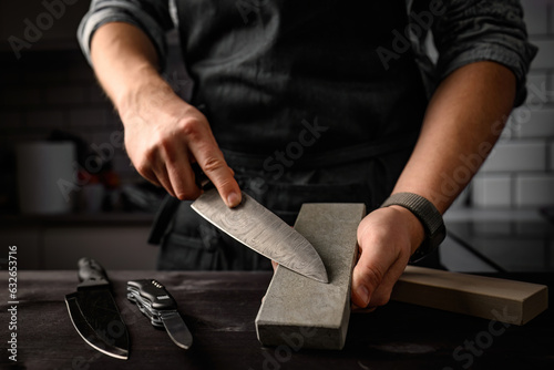 Man sharpening a knife with sharpen stone tool. Master sharpening knife on a grindstone photo