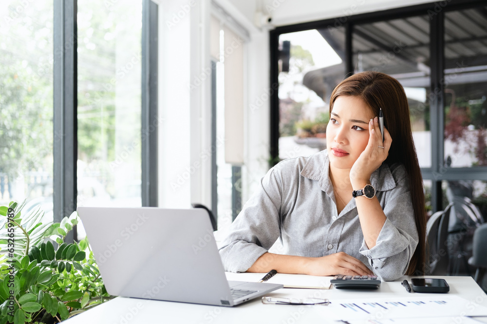 Young thoughtful Asian business woman executive manager wearing shirt working in modern office, taking notes and thinking of professional plan, project management, considering new business ideas. Young thoughtful Asian business woman executive manager wearing shirt working in modern office, taking notes and thinking of professional plan, project management, considering new business ideas.
