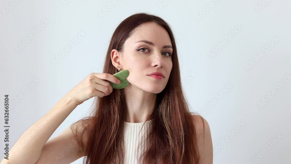 Close-up portrait of a beautiful girl, red-haired woman massaging her face with a stone scraper Close-up portrait of a beautiful girl, red-haired woman massaging her face with a stone scraper