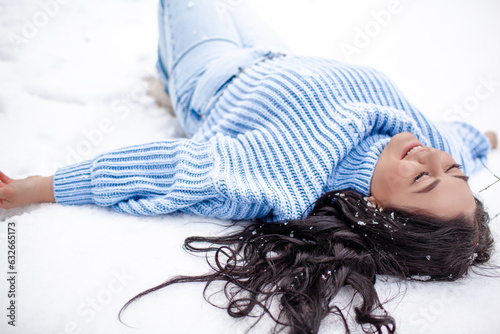 Beautiful woman wearing the blue knitted sweater, jeans and hat, the girl in warm cothes. Plus size woman waking, have fun in snow day photo