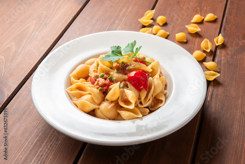 Piatto di deliziosa pasta italiana condita con ragu di pesce e pomodorini,  cibo mediterraneo 