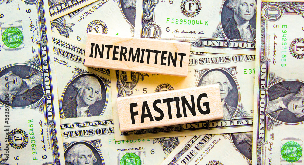 Intermittent fasting symbol. Concept words Intermittent fasting on wooden block. Beautiful background from dollar bills. Dollar bills. Healthy lifestyle intermittent fasting concept. Copy space.