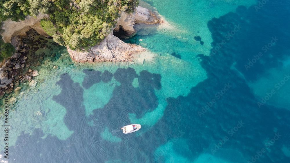 Family snorkeling near boat in clear tropical sea, aerial drone view from above
