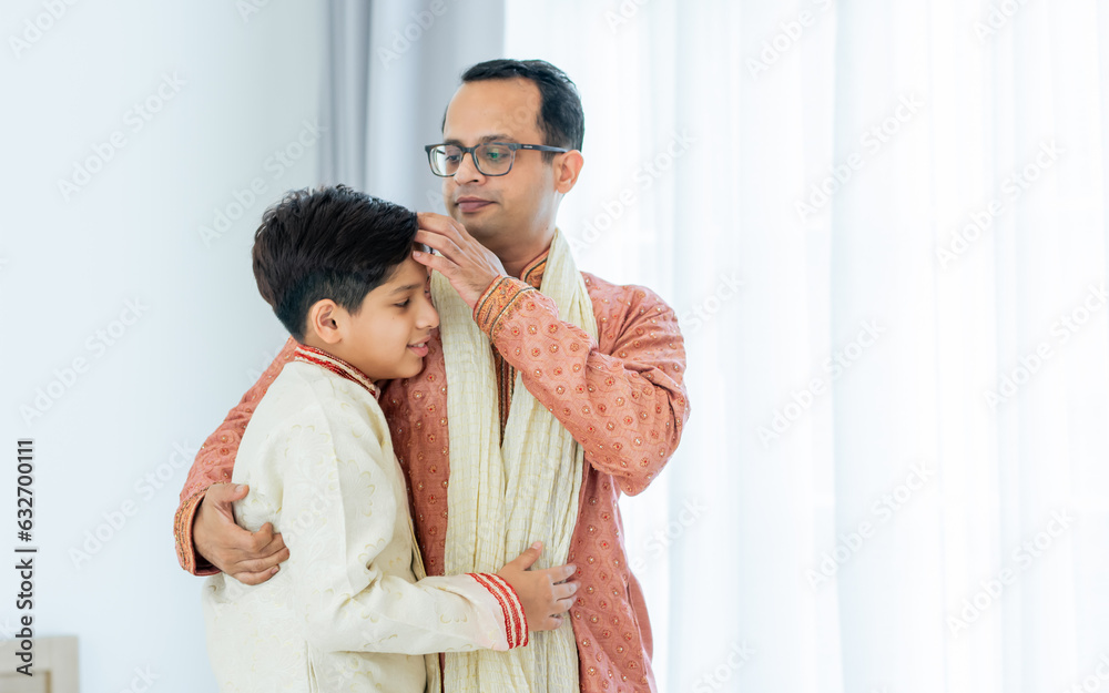 Two people of happy single Indian father, teenage handsome success son hugging with warmth, proud, love, wearing traditional clothes, smiling at home. Family, Education, Lifestyle Concept. Two people of happy single Indian father, teenage handsome success son hugging with warmth, proud, love, wearing traditional clothes, smiling at home. Family, Education, Lifestyle Concept.