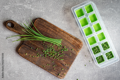 Green fresh organic chives on wooden cutting board ready to freeze. Overhead shot.