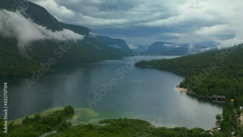 Aerial drone view of lake and green forest in the cloudily  morning. Clounds lay on mountains. Scenic View of water in a mountain forest, Bohinj lake with pine trees.  photo