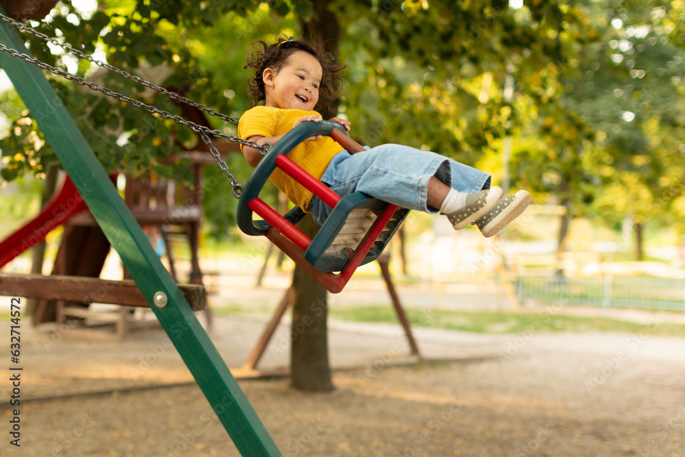 Obraz premium Joyful Japanese Baby Girl Swinging On Swings At Outdoor Playground