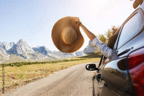 Woman hand holding wicker hat from car window, copy space