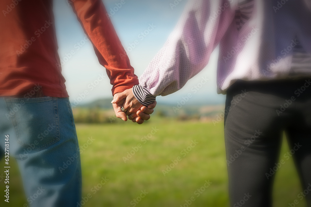 A couple is holding hands in the autumn or spring day in the park. Close-up of loving couple holding hands while walking. Selective focus
