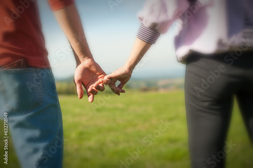 A couple is holding hands in the autumn or spring day in the park. Close-up of loving couple holding hands while walking. Selective focus