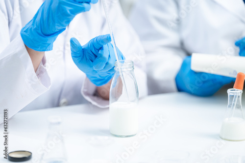 Food scientist testing new stuff samples of dairy products in the laboratory, female laboratory assistant checks a quality of milk, bottles glassware and glasses of milk to testing lactose forms