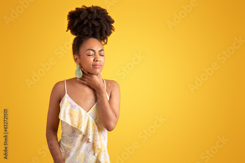 Unhappy millennial black woman presses hands to throat, suffering from pain, flu and cold photo