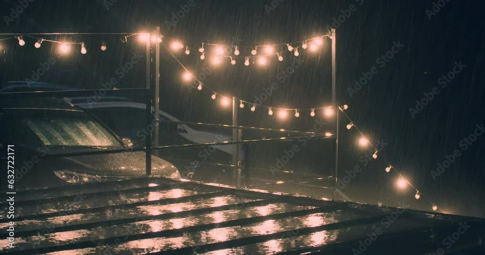 Torrential storm rain fall on street lights of terrace at night, static shot