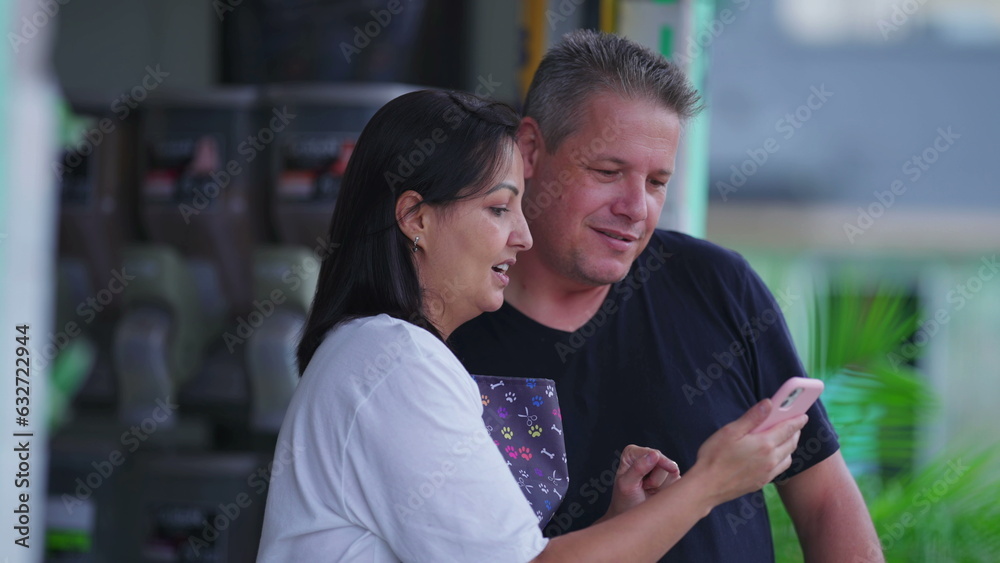 Woman showing smartphone screen to man. People looking at phone screen pointing with finger watching content online in street