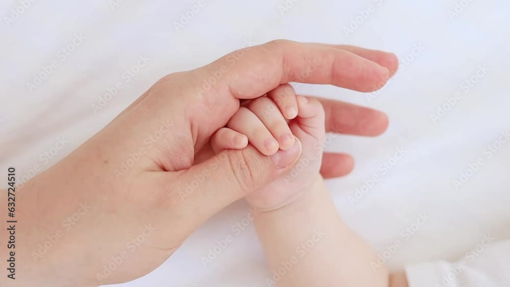 mom's hand gently strokes the handle of her newborn baby on the white bed at home, love and maternal care, mom and baby mom's hand gently strokes the handle of her newborn baby on the white bed at home, love and maternal care, mom and baby