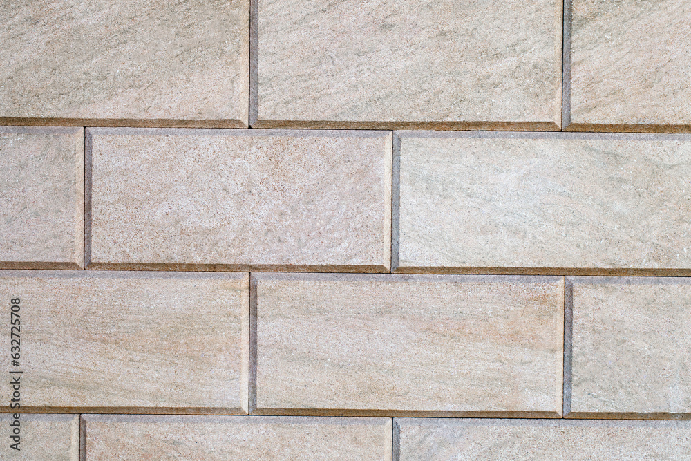 Fototapeta premium Wall is linked with decorative rectangular beige tiles, close-up, uniform texture background