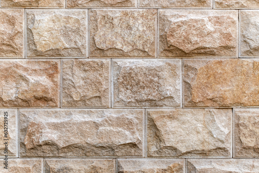 Fototapeta premium Wall lined with decorative chipped rectangular tiles, close-up, uniform texture background .