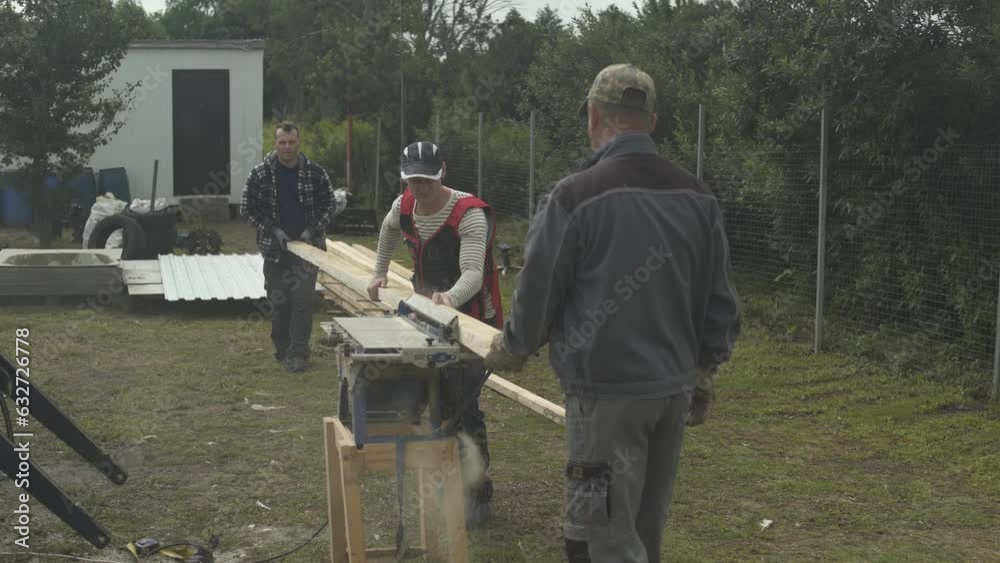 Builders sawing wood boards with circular saw machine on farm. Builders sawing wood boards with circular saw machine on farm.