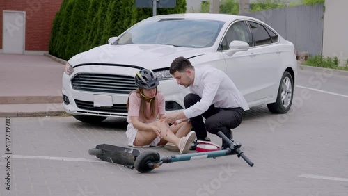 After a man hit a girl with a scooter with a car he was driving, he runs and brings her a box of medicines and bandages her knee. Concept of road accident and providing first aid in traffic