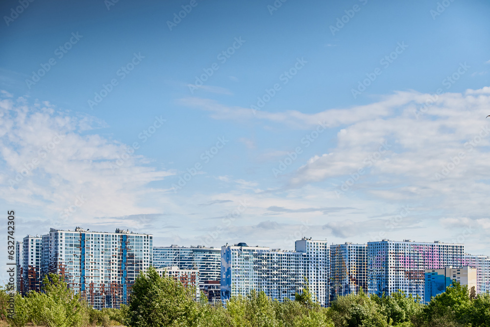 Obraz premium huge colorful residential complex in sunny weather, green vegetation in front of the buildings, facades of buildings, blue sky