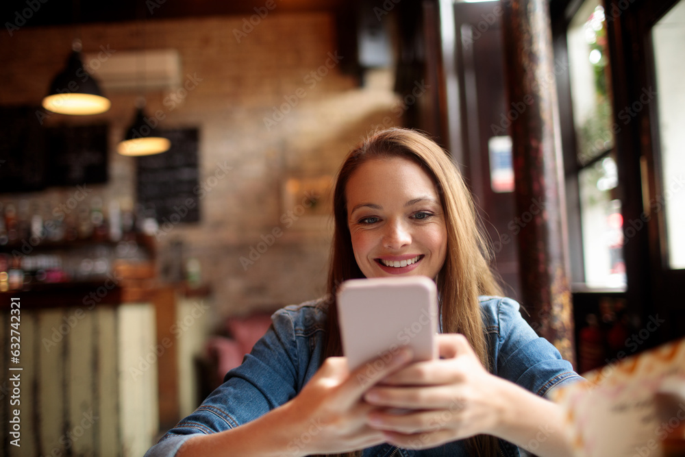 Young woman using a smart phone in a cafe in london Young woman using a smart phone in a cafe in london