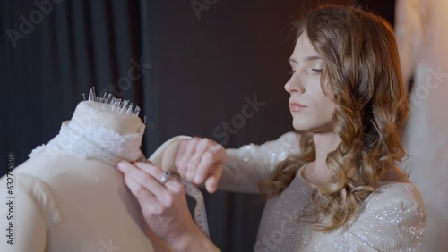 talented fashion designer gay man is modeling wedding dress in fashion atelier, non-binary queer man