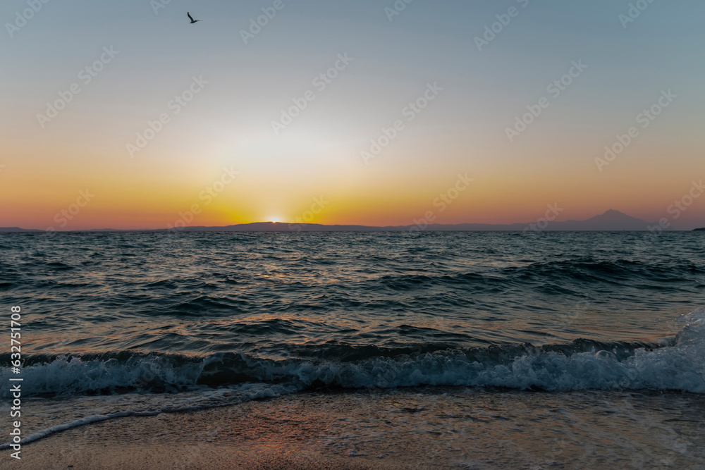 Beautiful sunrise over sea. The sun rises over the horizon at the dawn of the sea waves with splashes of water