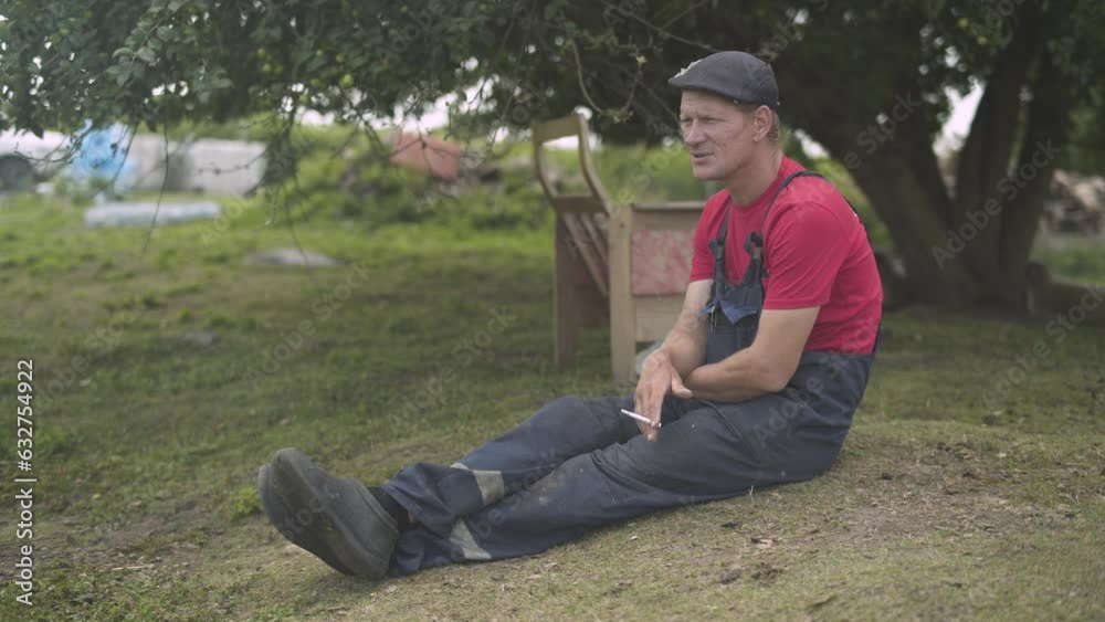 Farmer sitting on the grass smoking cigarette. Farmer sitting on the grass smoking cigarette.