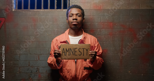 Black obedient prisoner begs for amnesty using cardboard with word Amnesty photo