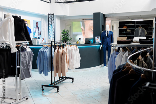 Clothing store interior with no people indoors displaying men and women formal wear on hangers. Fashionable retail shopping center showcasing trendy apparel hanging on racks