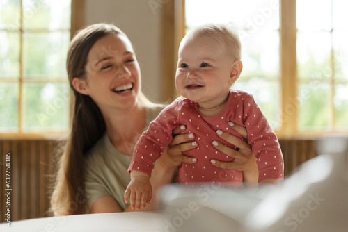 Bild auf Leinwand Cute nanny takes care of adorable child in kindergarten, holding her, smiling
