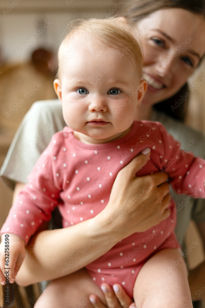 Cute nanny takes care of adorable child in kindergarten, holding her, smiling Cute nanny takes care of adorable child in kindergarten, holding her, smiling