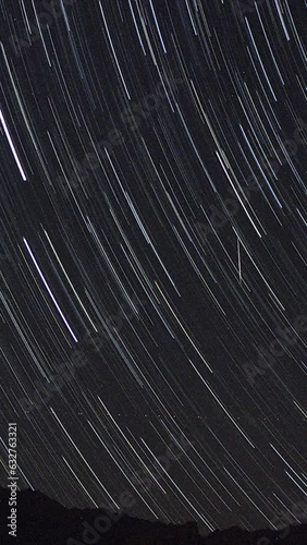 A view of the stars of the Milky Way with a mountain top in the foreground. Night sky nature summer landscape. Perseid Meteor Shower observation. Vertical video for social media. photo