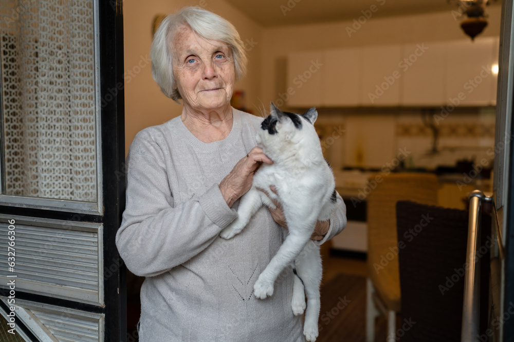 one woman senior old female caucasian pensioner standing at home alone waist up portrait look to the camera hold cat pet dementia alzheimer's disease and depression concept emotion copy space