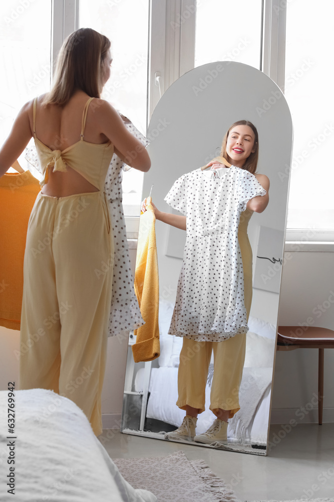 Young woman choosing clothes in front of mirror at home Young woman choosing clothes in front of mirror at home