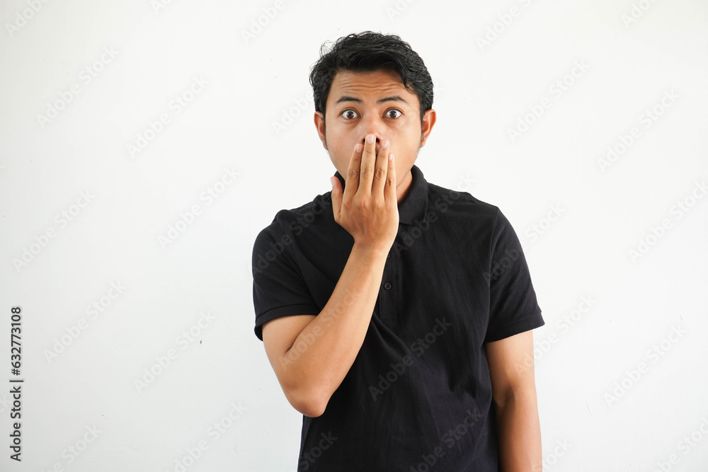 young asian man close his mouth with hands and showing shocked expression wearing black polo t shirt isolated on white background