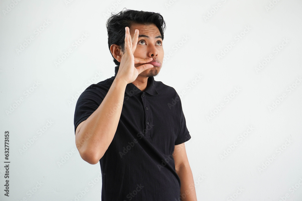 young Asian man shut his mouth up with serious expression, with fingers on lips keeping a secret. wearing black polo t shirt isolated on white background young Asian man shut his mouth up with serious expression, with fingers on lips keeping a secret. wearing black polo t shirt isolated on white background