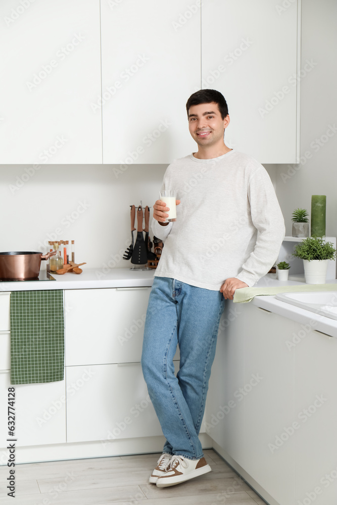 Young man with glass of milk in kitchen