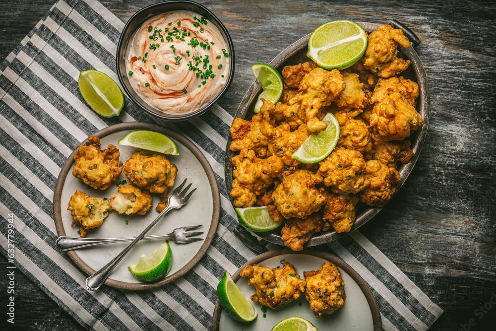 Shrimp Fritters in basket and plate with dipping sauce and limes Shrimp Fritters in basket and plate with dipping sauce and limes